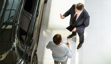 Revendedor de carros falando sobre os benefícios da película para vidros para cliente 