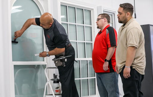 Architectural window film installer showing trainees proper installation technique 